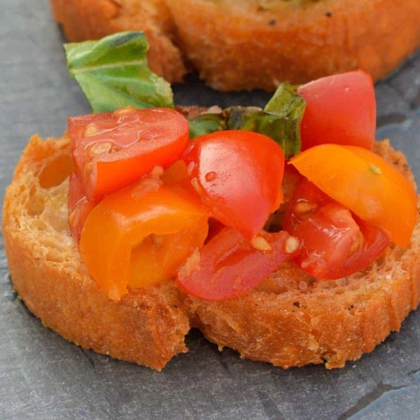 This Tomato Bruschetta recipe is a classic no cook appetizer that can be ready in as little as 20 minutes using fresh tomatoes, basil and garlic. #easybruschetta #tomatobruschetta www.savoryexperiments.com