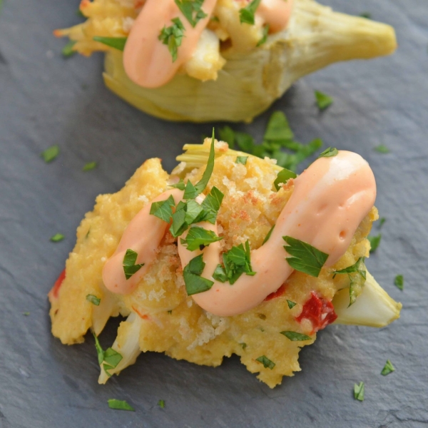 Crab Dip Stuffed Artichoke Hearts takes traditional hot crab dip and bakes in an artichoke heart, topping it with crunchy panko and Sriracha Aioli. #hotcrabdip #artichokerecipes #crabappetizers www.savoryexperiments.com