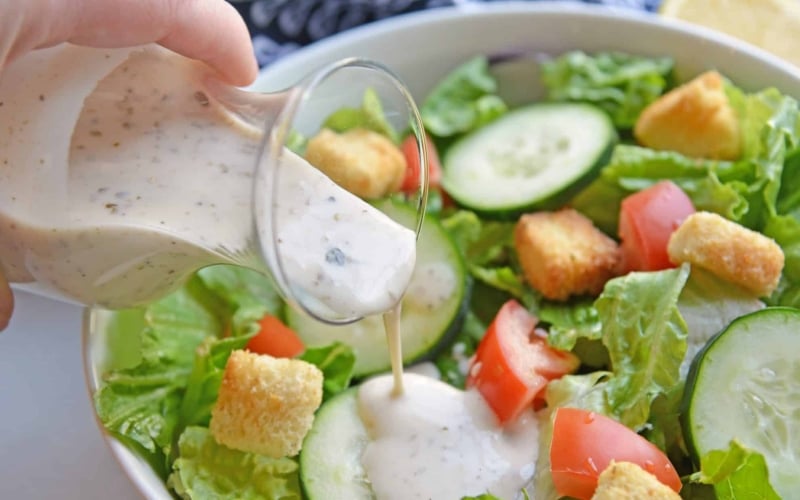 creamy salad dressing pouring onto salad