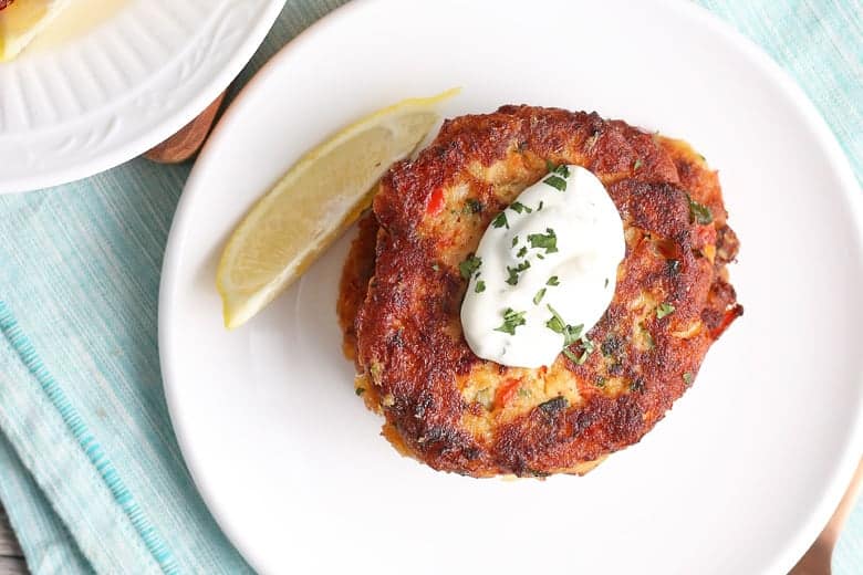 Overhead of salmon cakes with a lemon slice on a white plate 