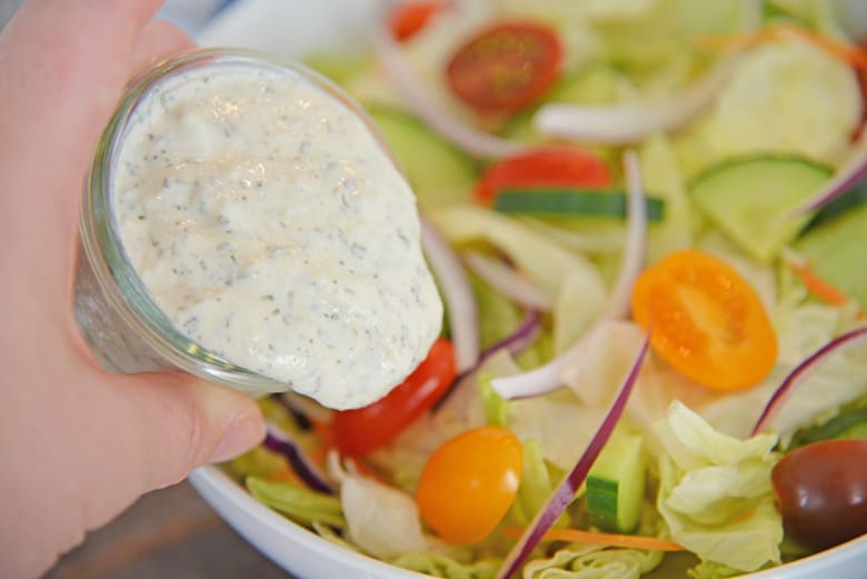 Ranch dressing pouring onto a salad 