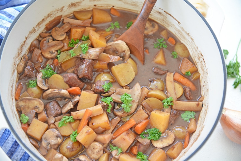 wooden spoon in a pot of red wine beef stew 