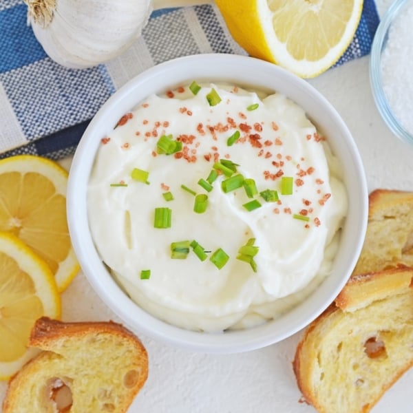 overhead bowl of garlic aioli with lemons and crostini