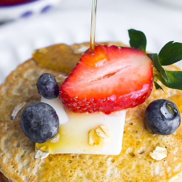 oatmeal pancakes drizzled with maple syrup and fresh fruit