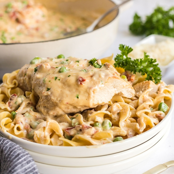 creamy garlic chicken over noodles on white plate