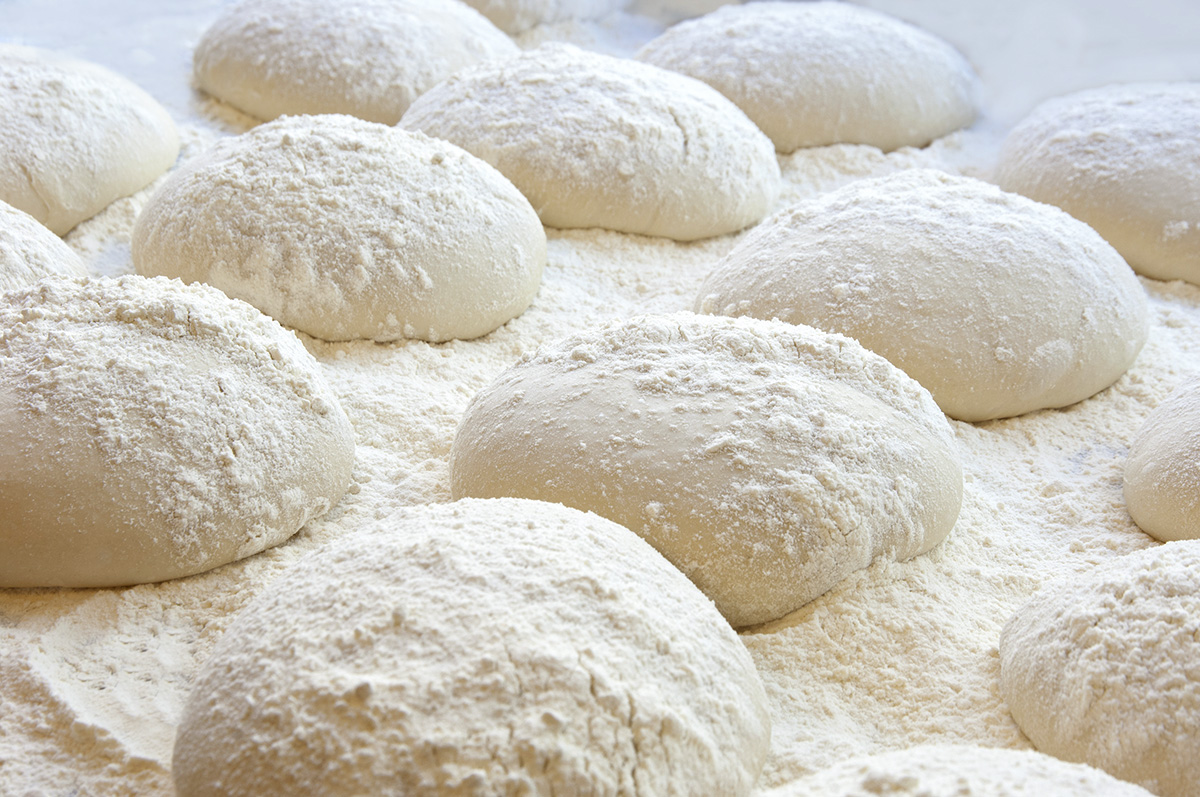 many dough balls surrounded by flour 