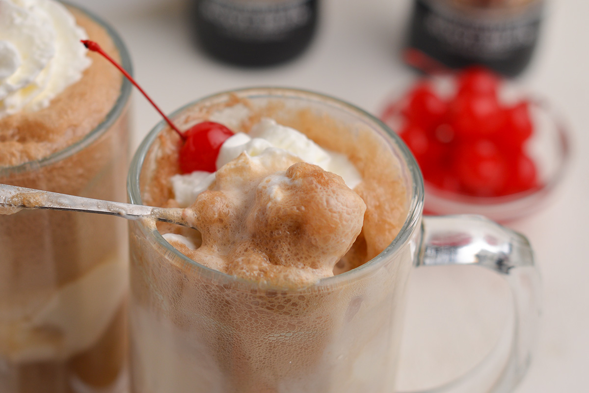 spoon dipping into a root beer float with lots of froth and bubbles 