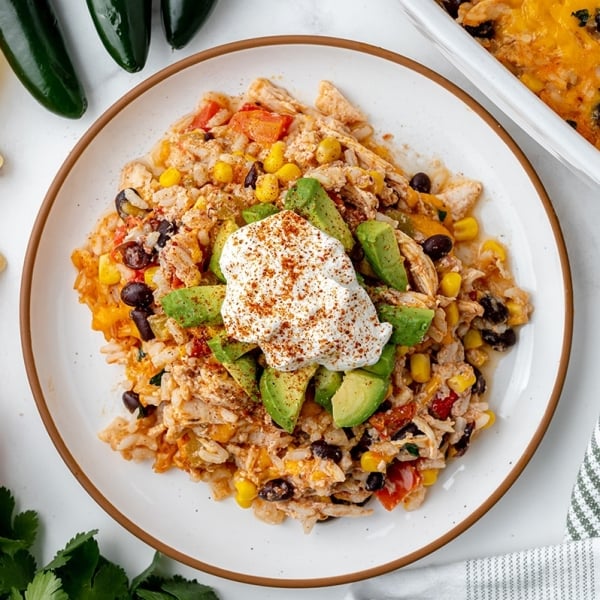 plate of chicken casserole topped with avocado and sour cream