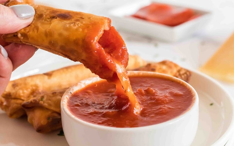 close up of pizza log dipped into sauce