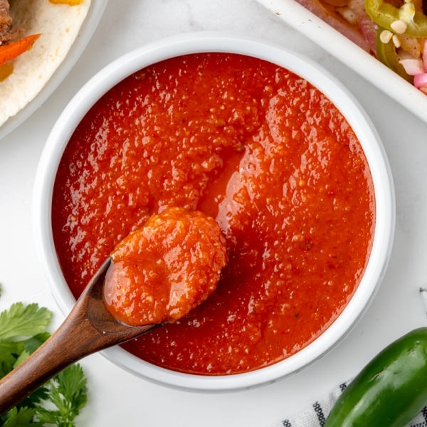 wooden spoon in bowl of ranchero sauce