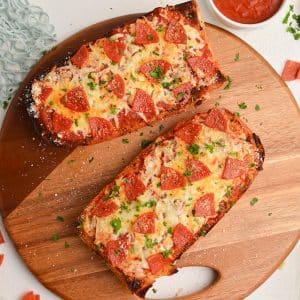 two pieces of french bread pizza on a wooden board