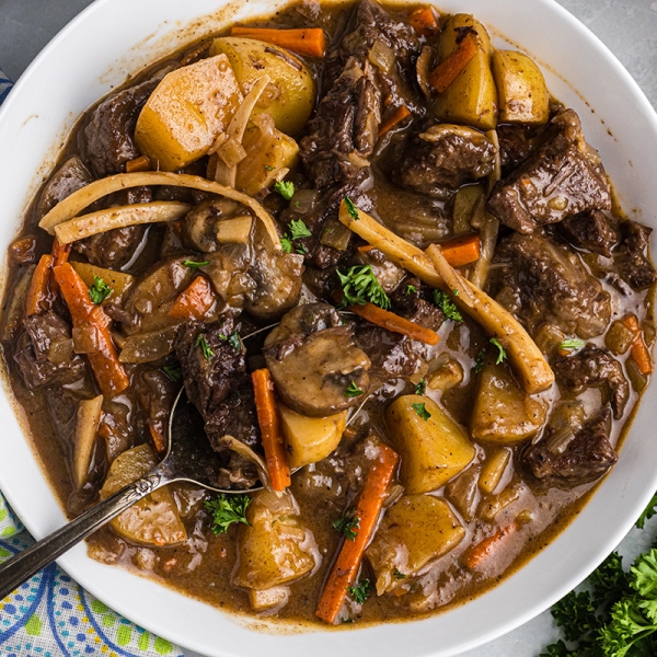 close up overhead shot of spoon in bowl of beef stew