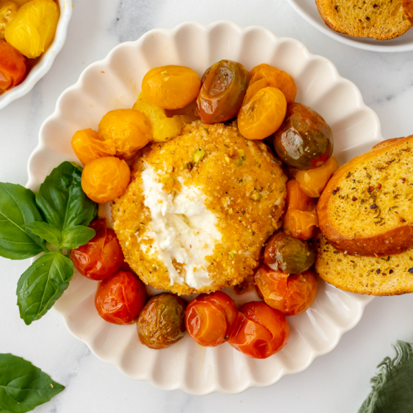 overhead shot of air fryer burrata on plate with tomatoes and garlic bread with scoop taken out