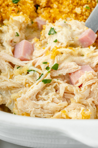close up angled shot of serving spoon scooping up chicken cordon bleu casserole