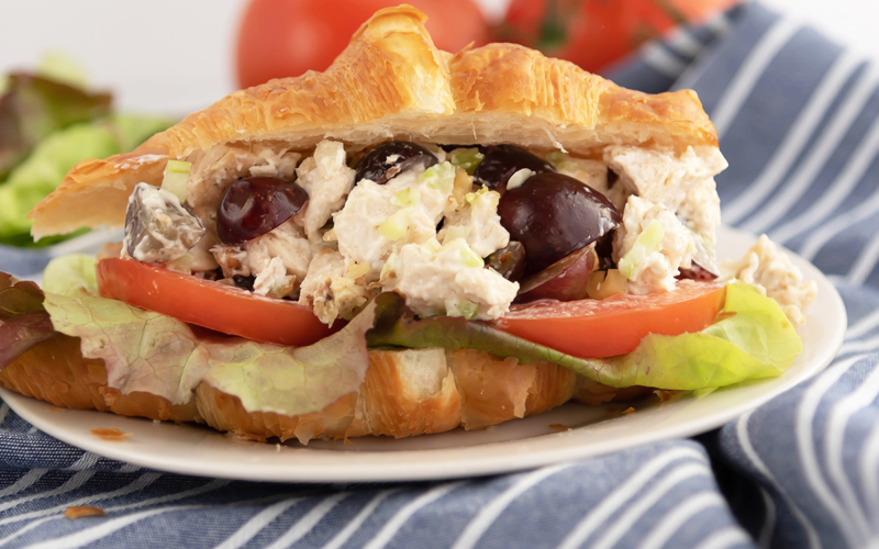 A close up of a sandwich on a plate, with Chicken and Salad