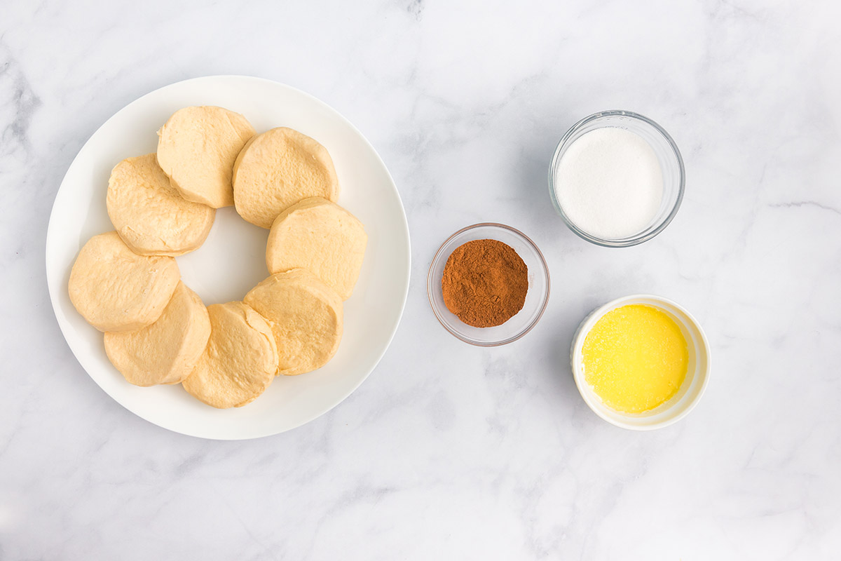 ingredients for air fryer donuts - biscuit dough, cinnamon, sugar and butter