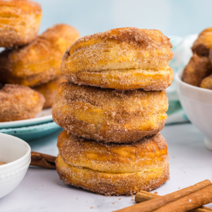 stack of three donuts with bowl of donut holes in the back