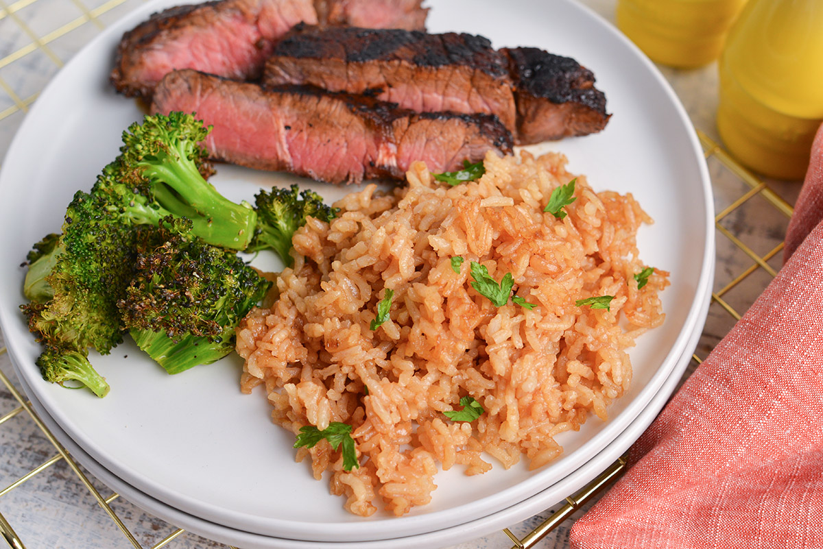 angled shot of plate of steak with broccoli and butter rice