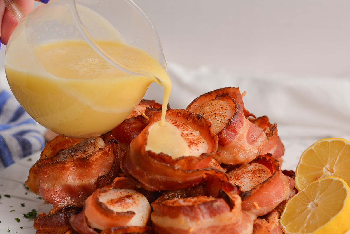 sauce pouring over bacon wrapped scallops