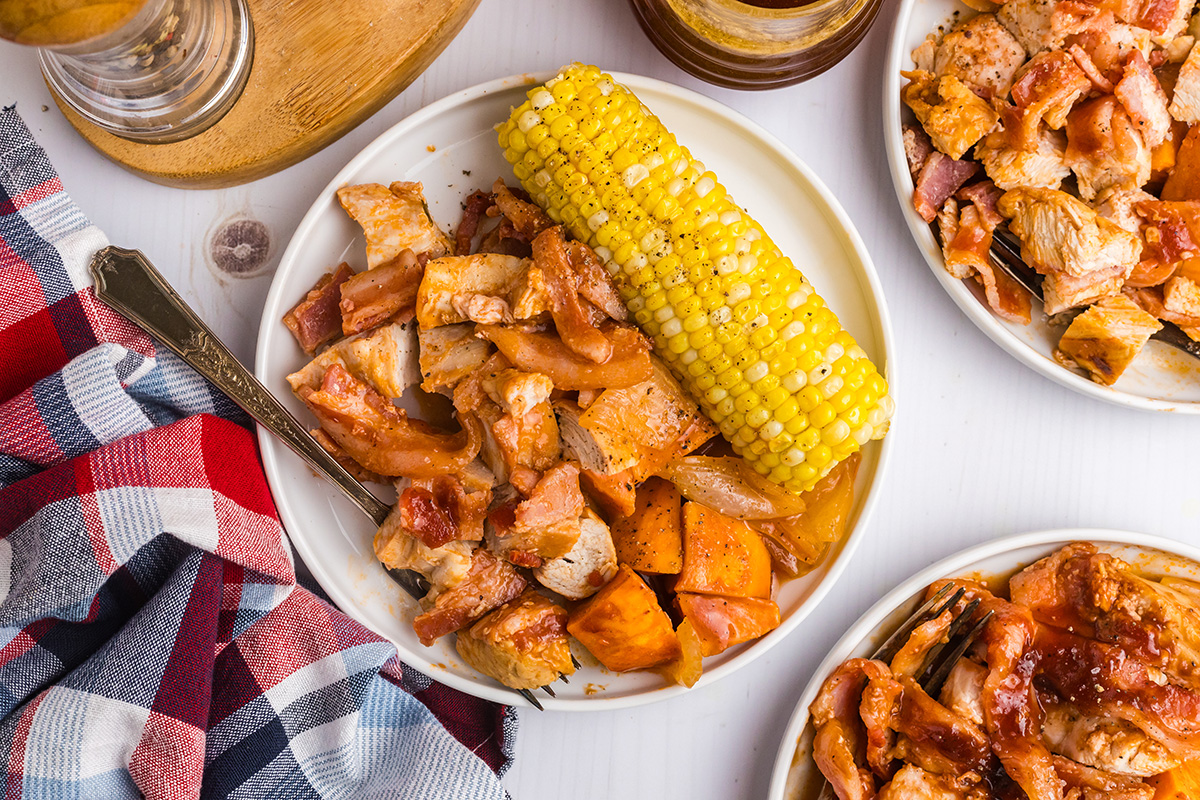 overhead shot of plate of bbq chicken, sweet potatoes and corn on the cob