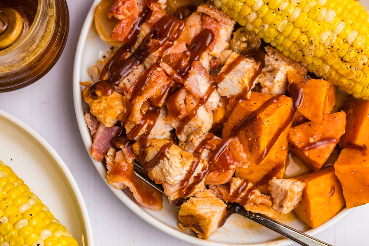 overhead shot of bbq chicken and sweet potatoes on plate with corn