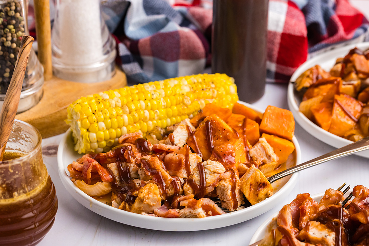 bbq chicken and sweet potatoes on plate with corn on the cob