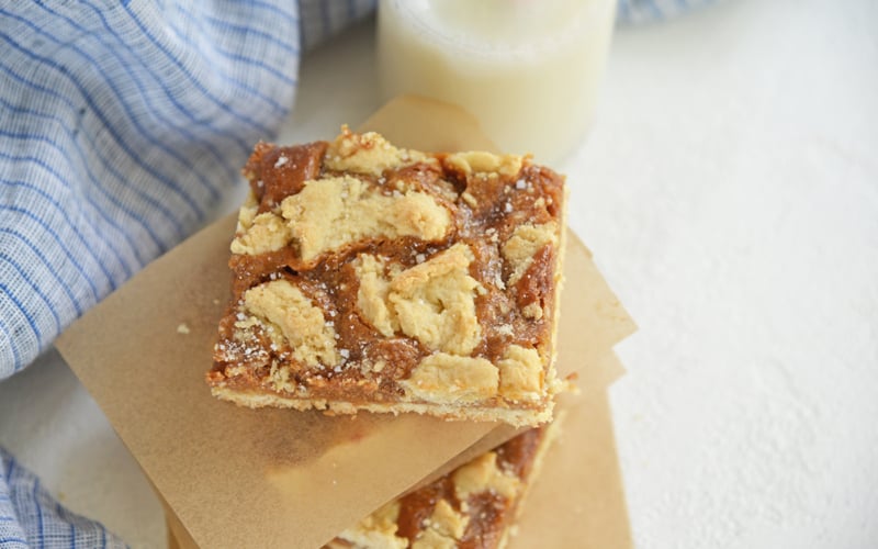 dulce de leche bars stacked between parchment with blue linen