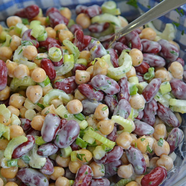 mixing beans together with yogurt, scallions and celery