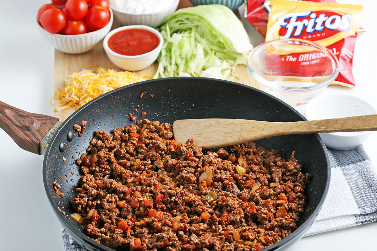 angled shot of taco meat in pan with wooden spoon