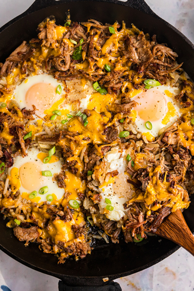 overhead shot of wooden spoon in bbq pulled pork hash in skillet