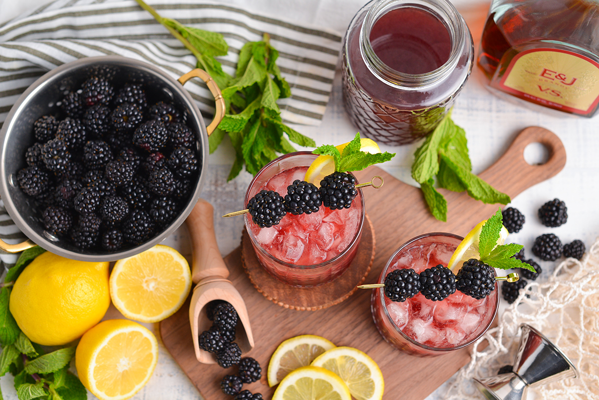 overhead shot of two blackberry bourbon cocktails with bowl of blackberries