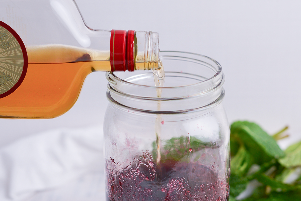 brandy pouring into jar of blackberries