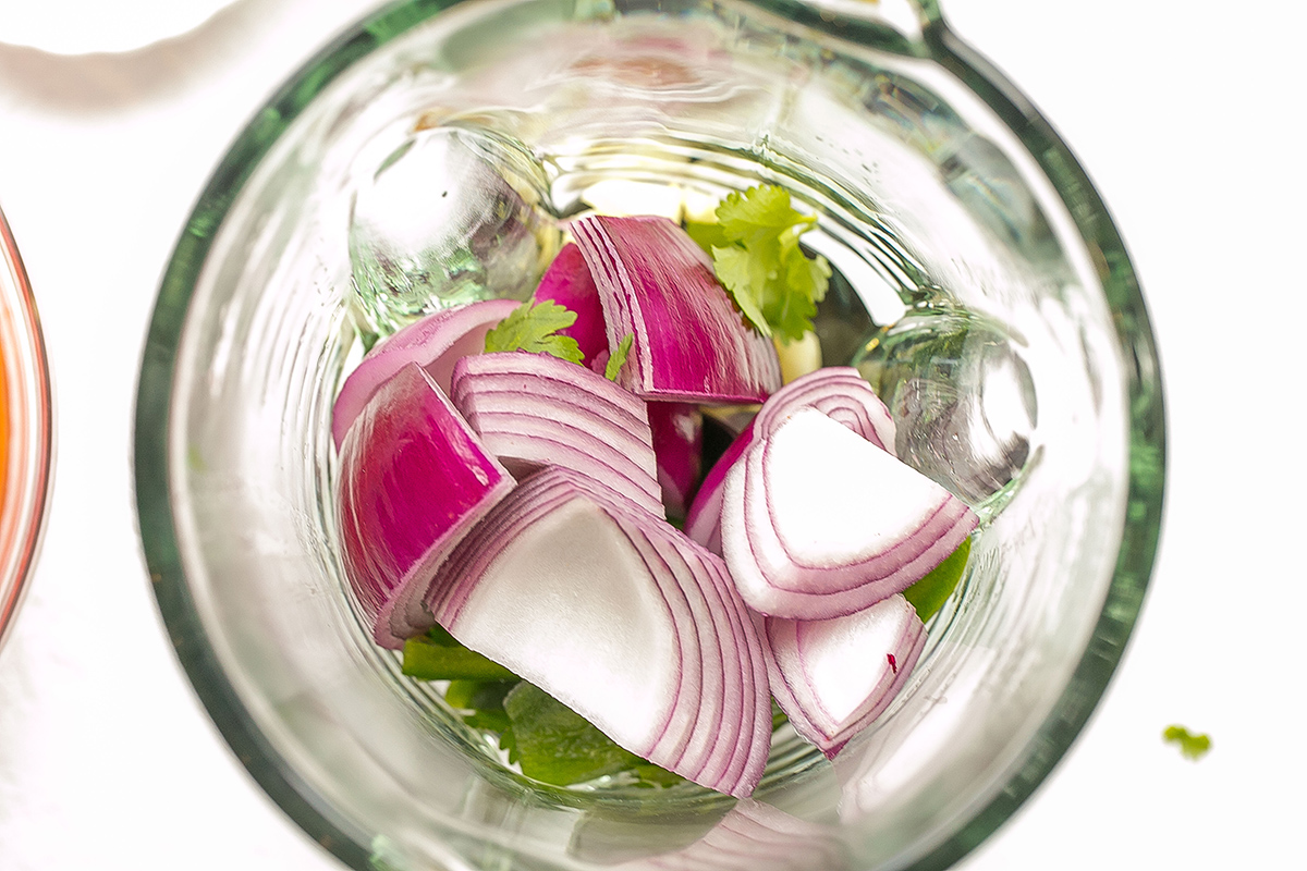 overhead shot of onion and cilantro in blender