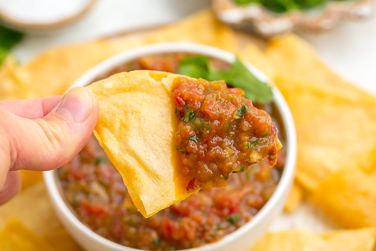 close up of hand holding chip with salsa made in a blender on it