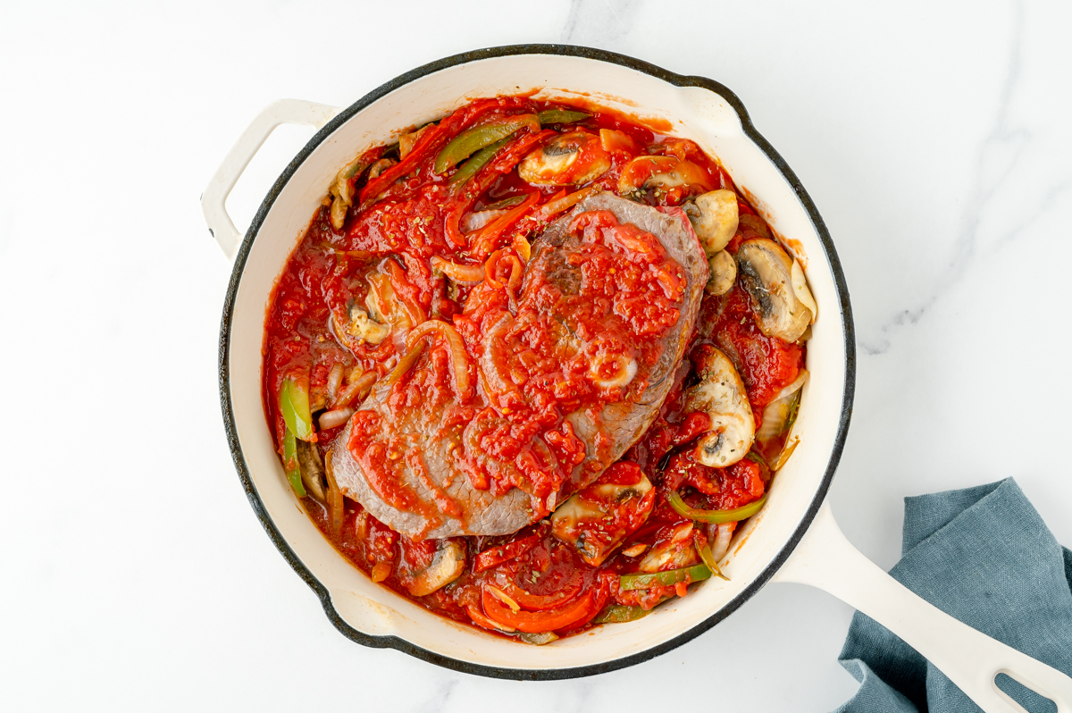 overhead shot of steak in pan with sauce and veggies