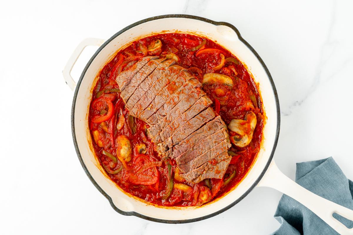 overhead shot of sliced steak in pan with sauce and veggies