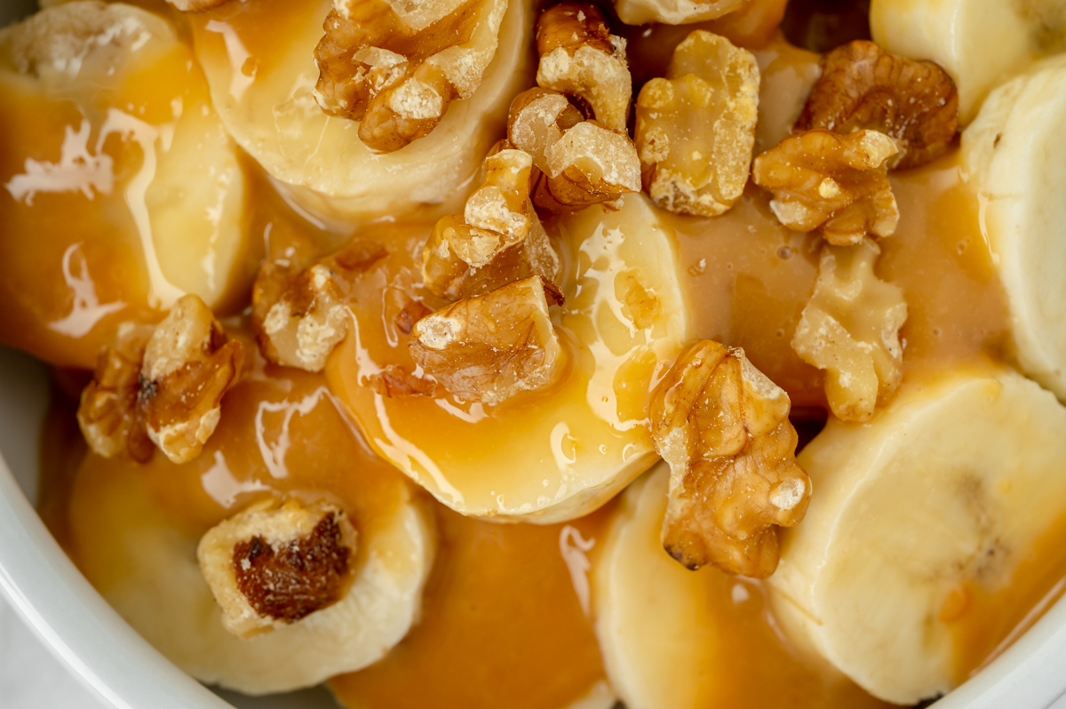 close up overhead shot of sweetened condensed milk caramel over sliced bananas and walnuts