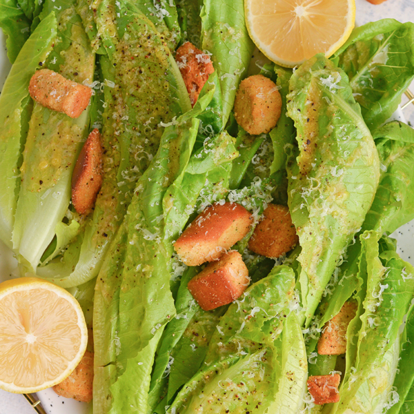 close up of romaine lettuce with garlic salad dressing, and fresh lemons