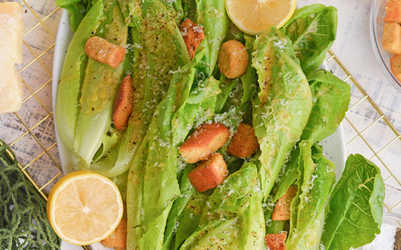 close up of romaine lettuce with garlic salad dressing, and fresh lemons