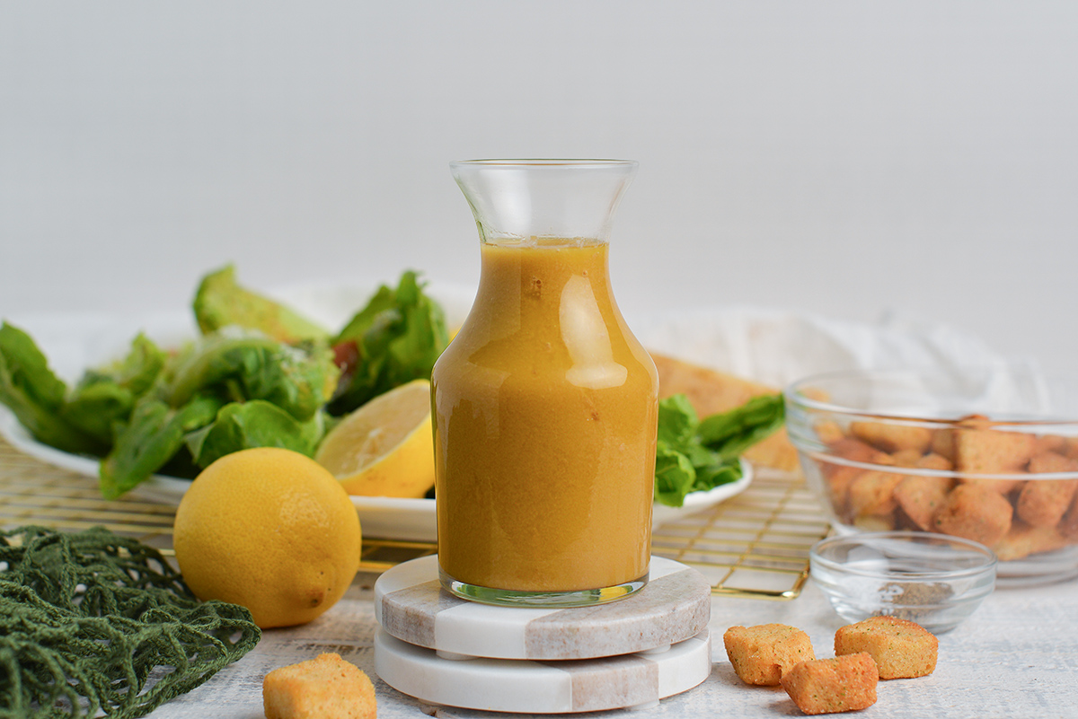 bottle of garlic dressing in a glass bottle on coasters with salad ingredients around it