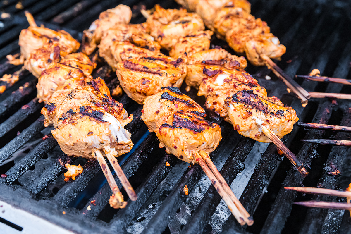 angled shot of harissa chicken kabobs on grill