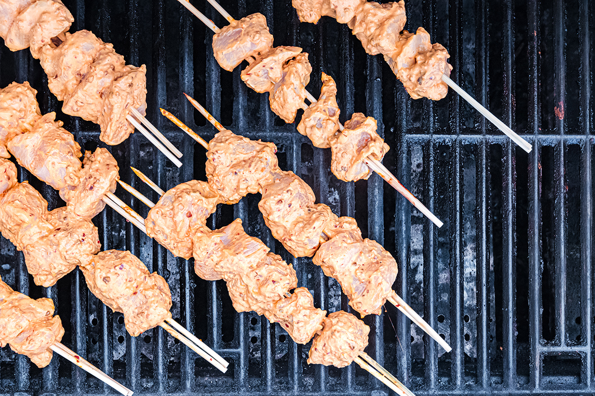 overhead shot of harissa chicken kabobs cooking on grill