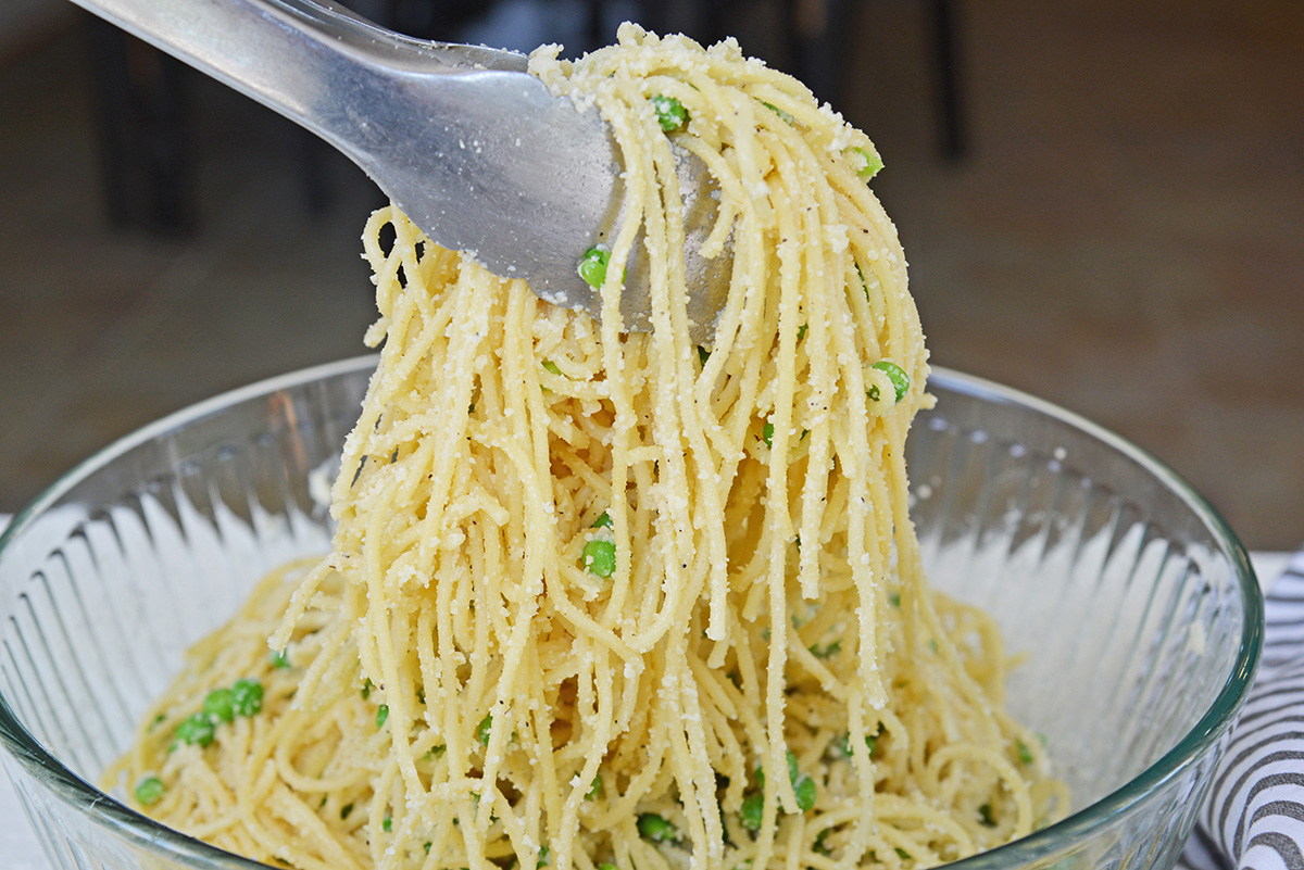 tongs holding spaghetti with cheese