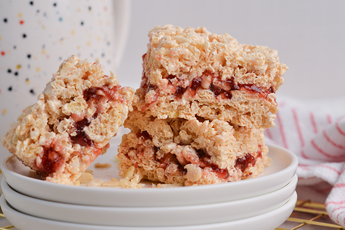 close up shot of peanut butter and jelly rice krispie treats on a stack of plates