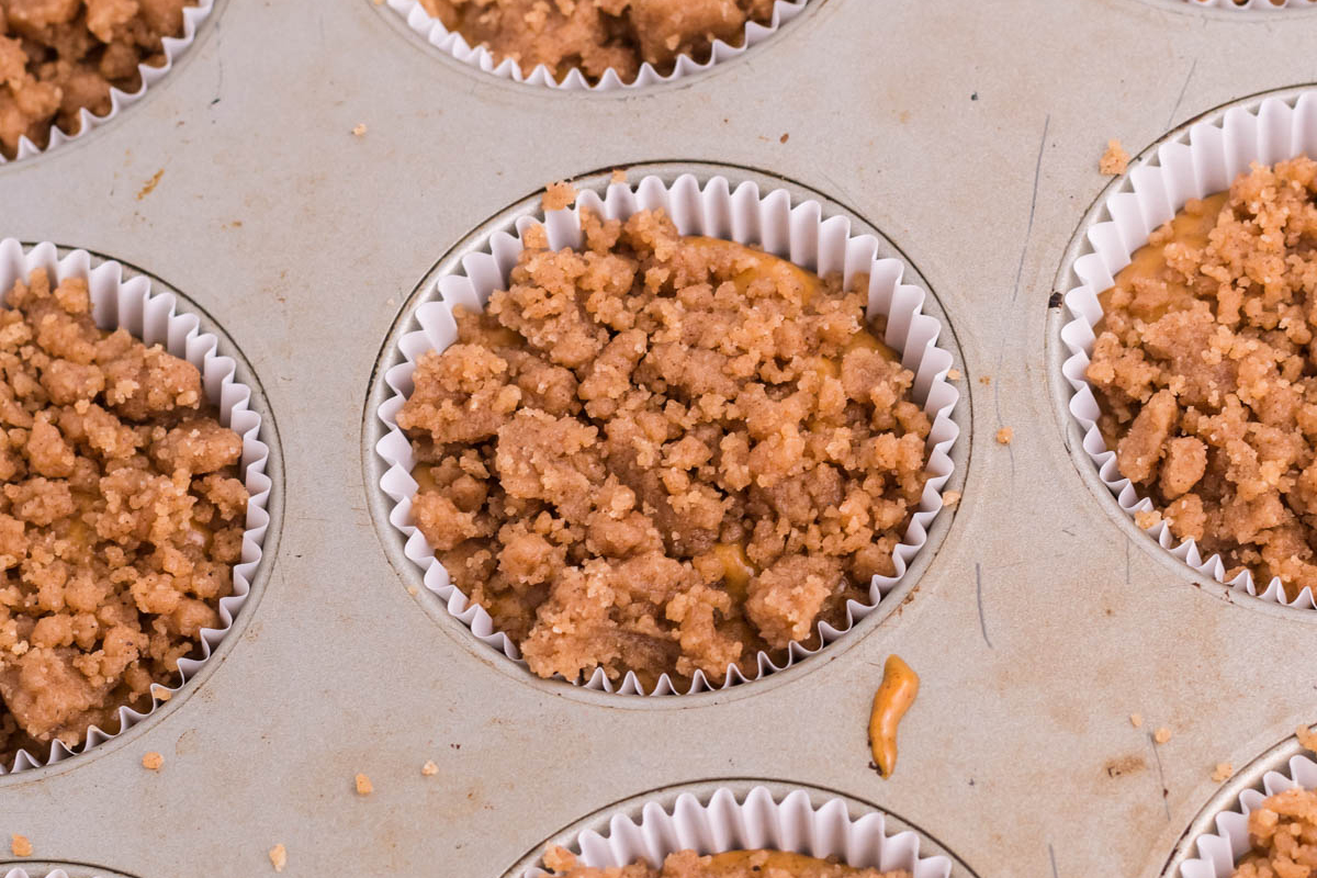 overhead shot of streusel over pumpkin muffin batter