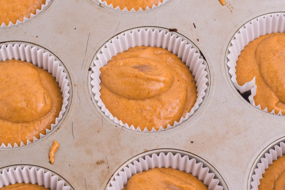 angled shot of pumpkin muffin batter in muffin tin