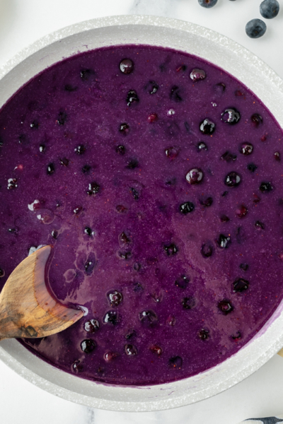 overhead shot of wooden spoon in pan of blueberry syrup