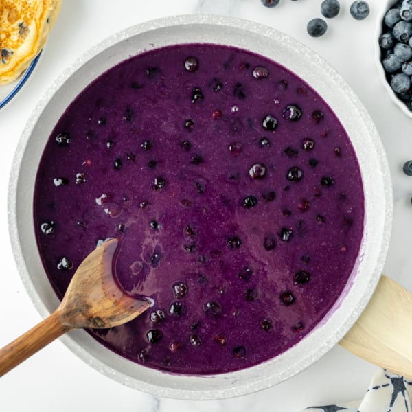 overhead shot of wooden spoon in pan of blueberry syrup