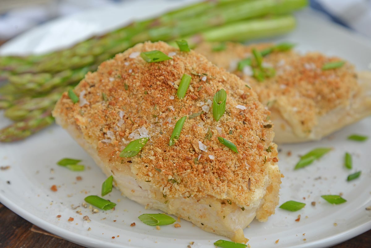 garlic parmesan chicken on a white plate with asparagus