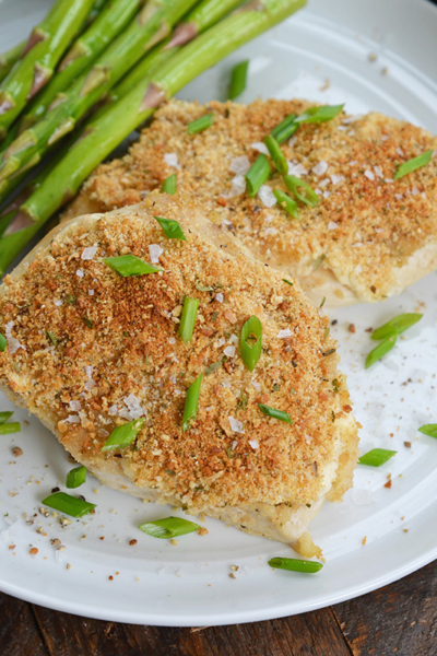 garlic parmesan chicken on a white plate with asparagus